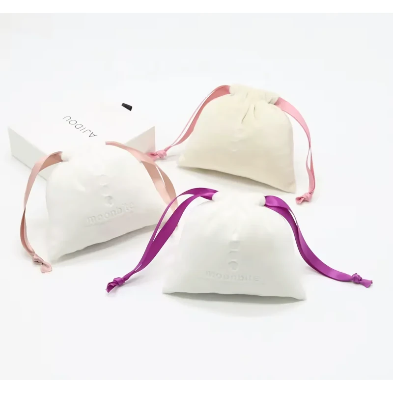 Three ivory gift pouches with blush, pink and purple ribbon ties.