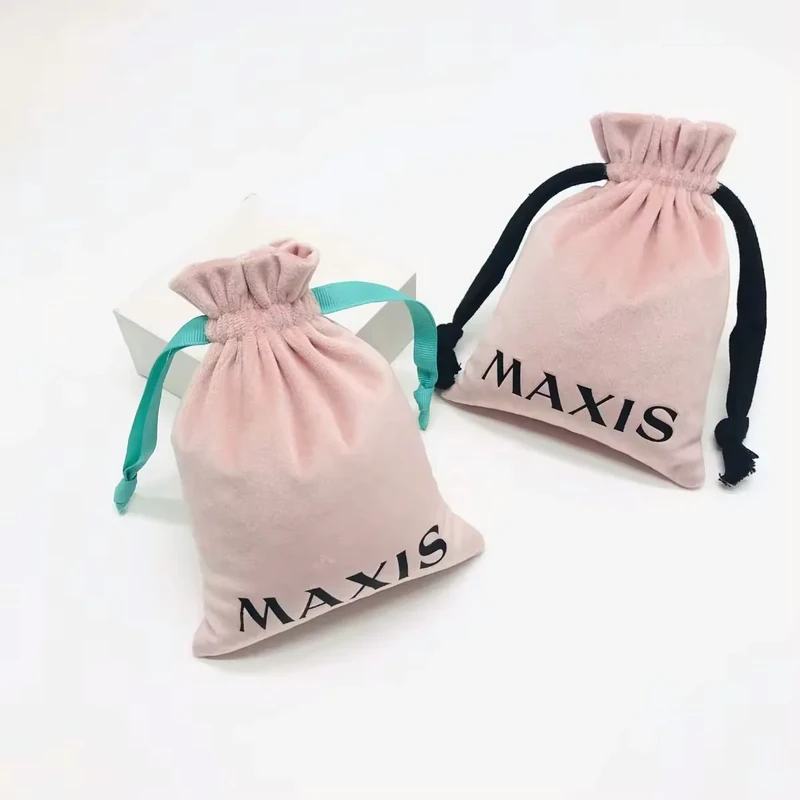 Two blush jewelry pouches with printed logos and contrasting black and turquoise ribbon ties