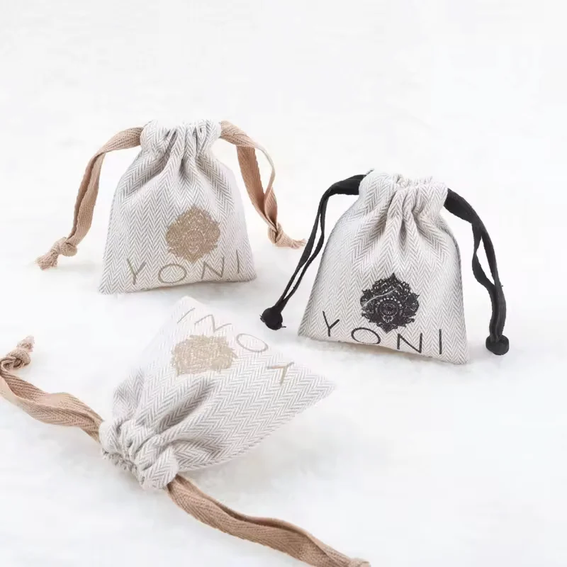 Three small cotton drawstring pouches with printed botanical logos and contrasting cords