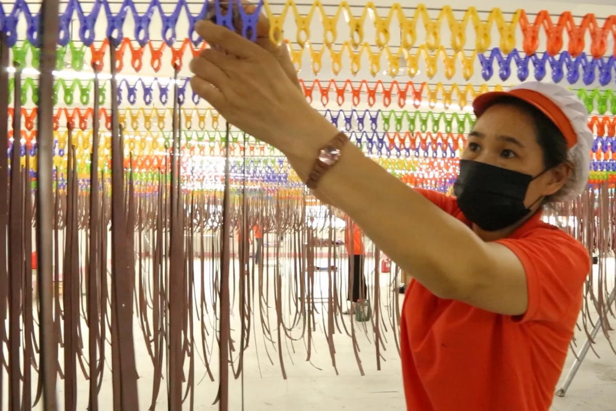 An operator arranging narrow bag components on a hanging rack.