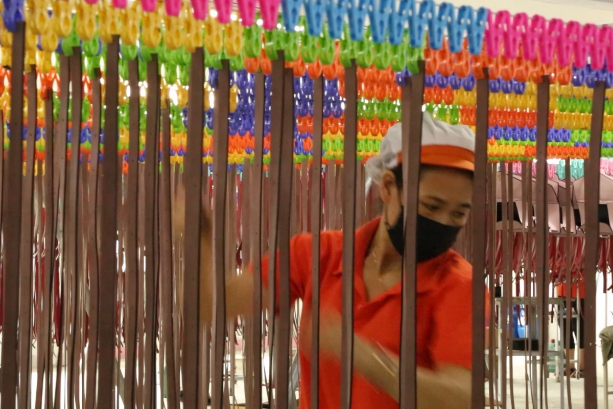 An operator working behind rows of narrow bag components on hanging racks.