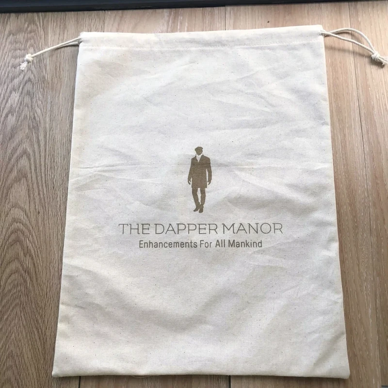 Empty natural cotton drawstring bag laid flat to show the body and seams
