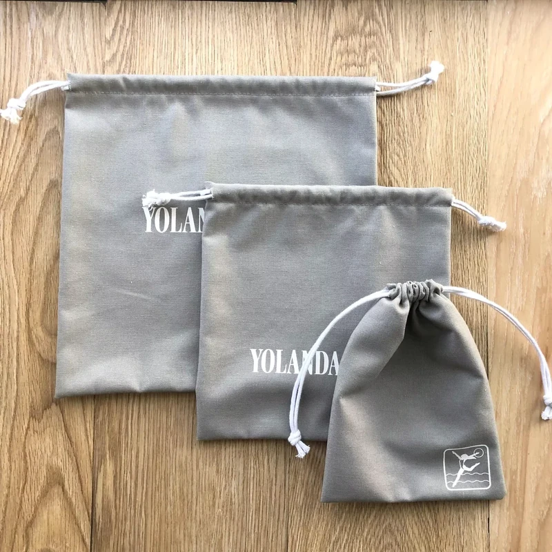 Three gray drawstring bags laid flat to compare their outer sizes