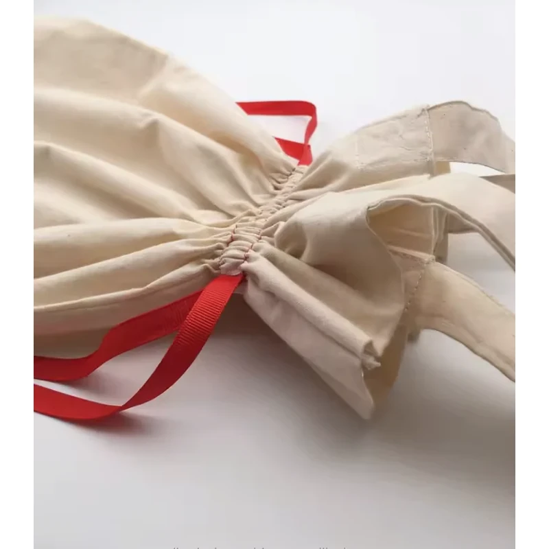 Close-up of a gathered cotton bag opening with handles and red drawstring cords
