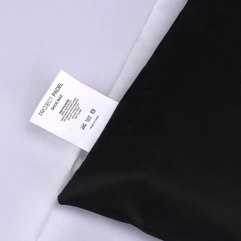 A white care label sewn into the side seam of a black fabric bag.