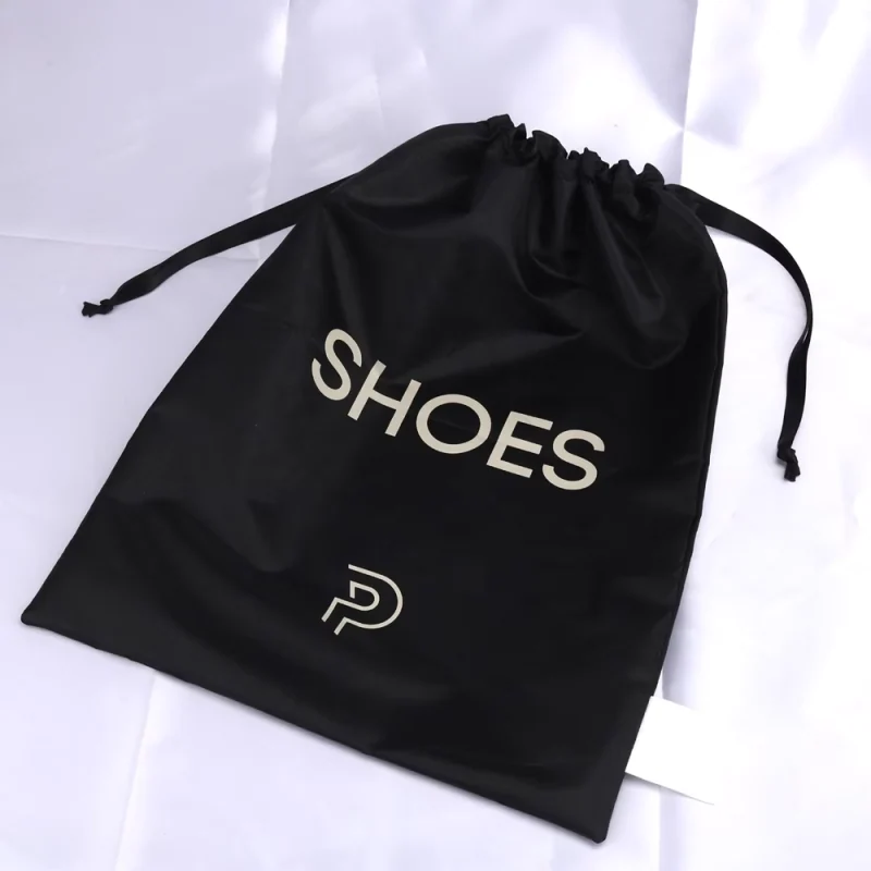 Black printed drawstring shoe pouch laid flat with its ribbon ties visible