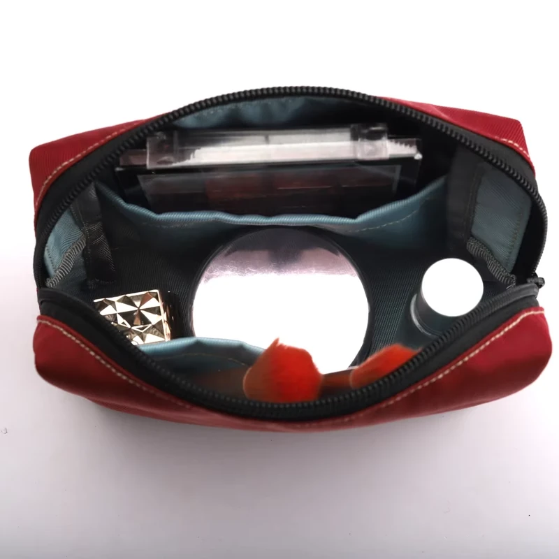 Open red travel pouch with cosmetics arranged in its main compartment and inner pockets