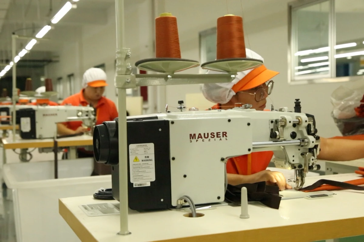 An industrial sewing machine and tall thread cones at an active workstation.