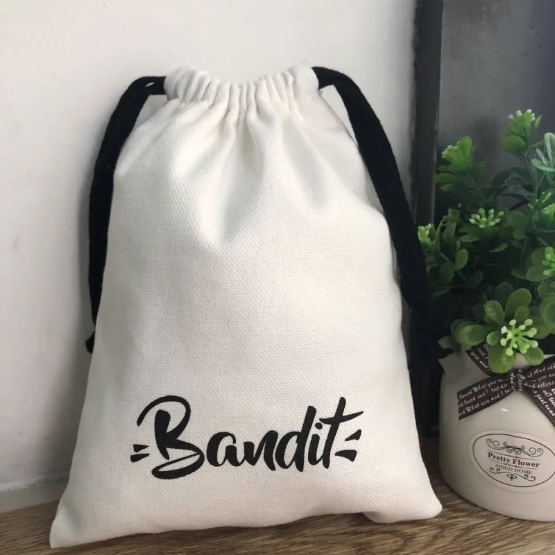 A natural cotton drawstring bag with black ribbons.