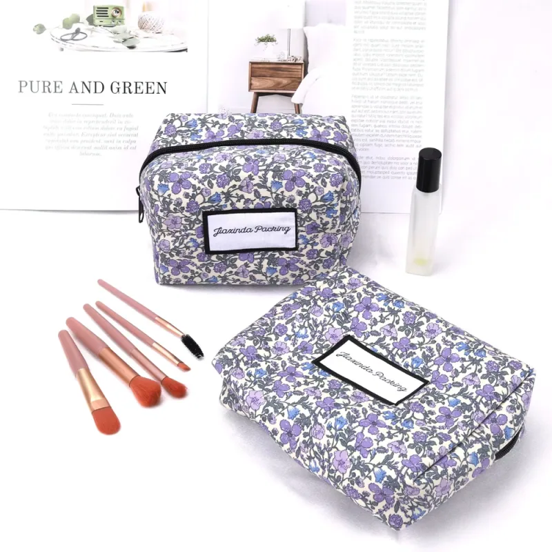 Two floral cosmetic zipper bags beside makeup brushes.