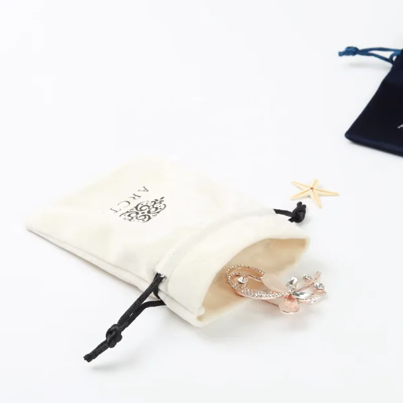 An ivory drawstring pouch with jewelry at its open mouth.
