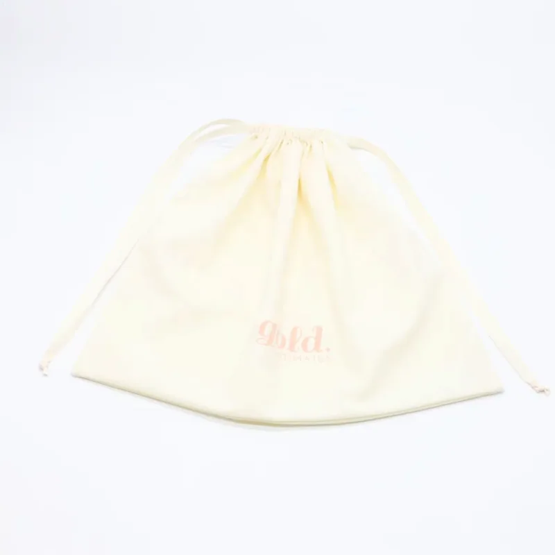 An ivory cotton dust bag laid flat with ribbon drawstrings.