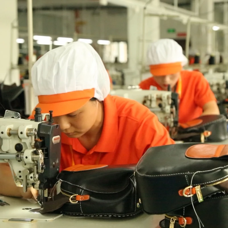 An operator stitching a black bag at an industrial sewing machine.