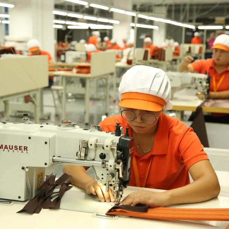 An operator guiding bag components through an industrial sewing machine.