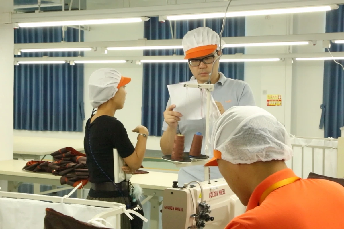 Team members discussing work beside a sewing station.