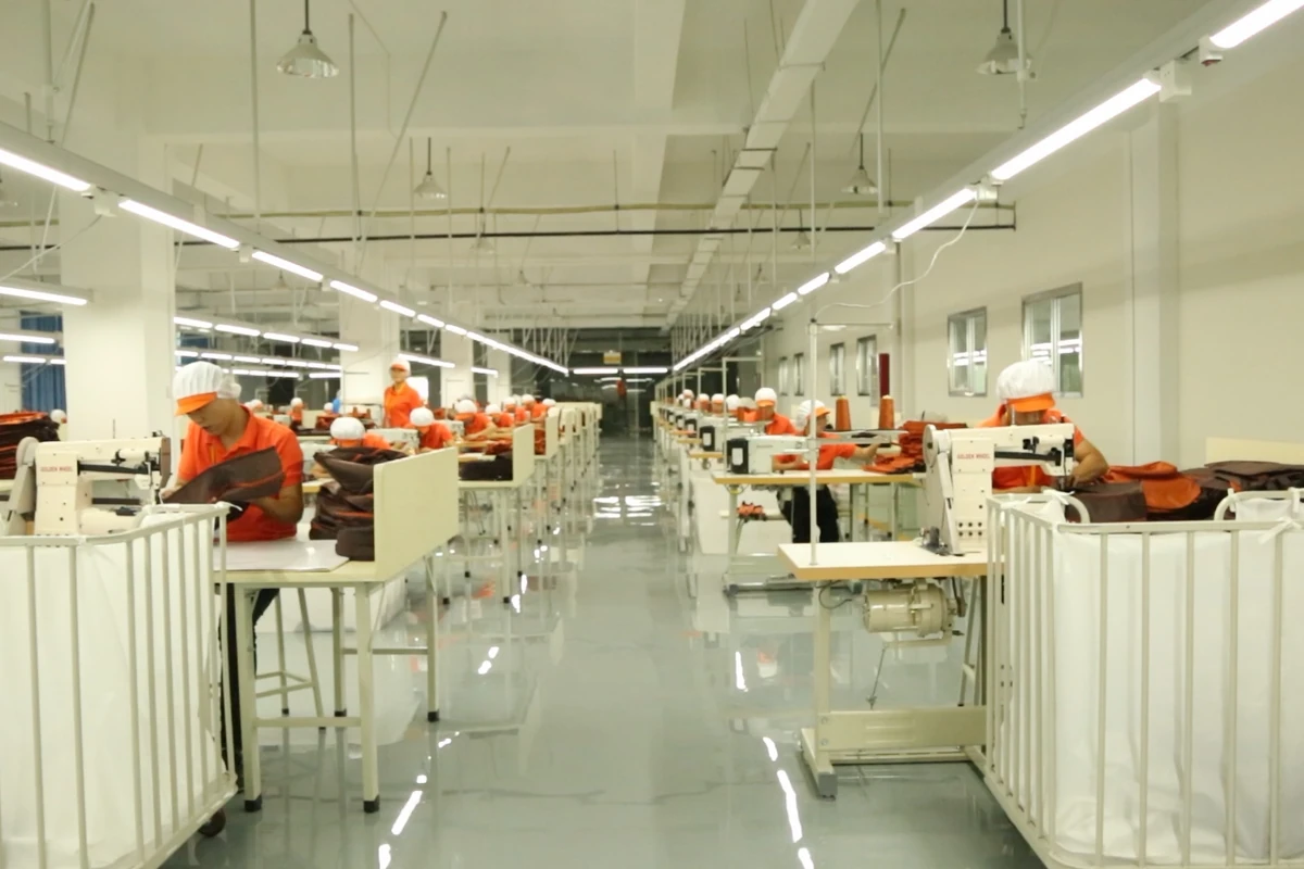 A central aisle between sewing workstations and wheeled material carts.